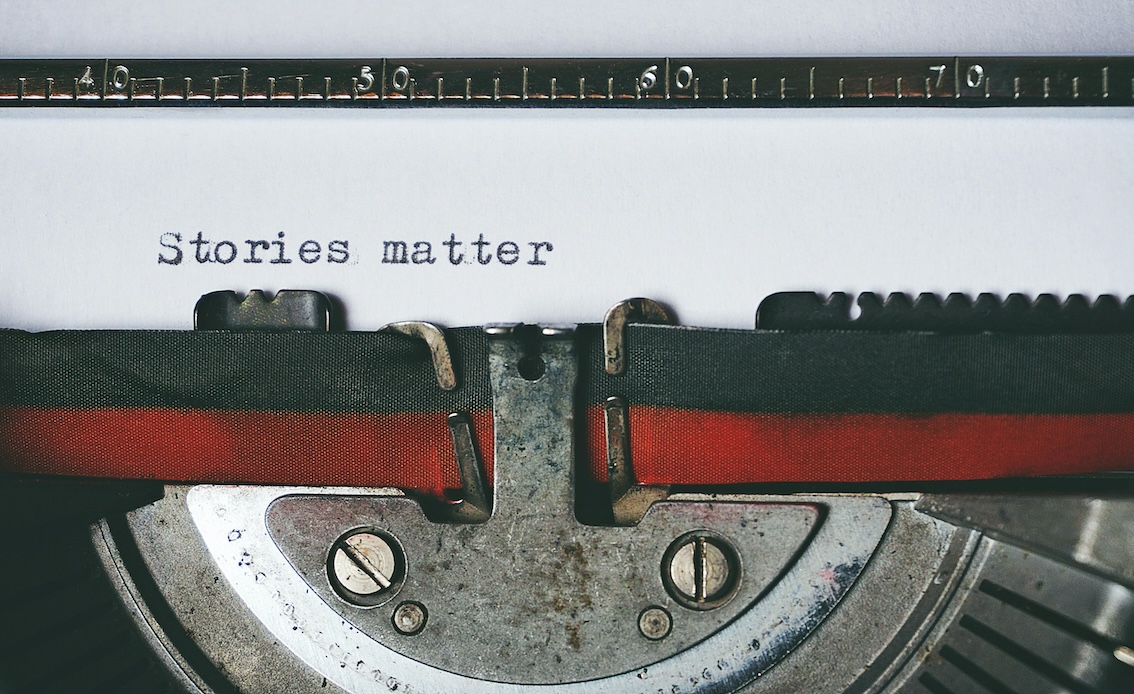 old typewriter with a white paper with written stories matter